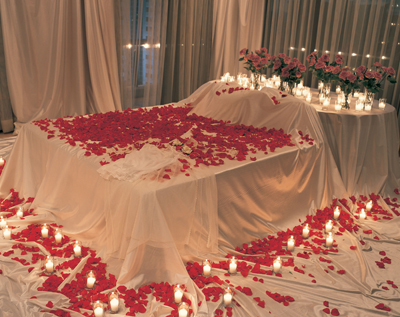 Scatter rose petals on bed